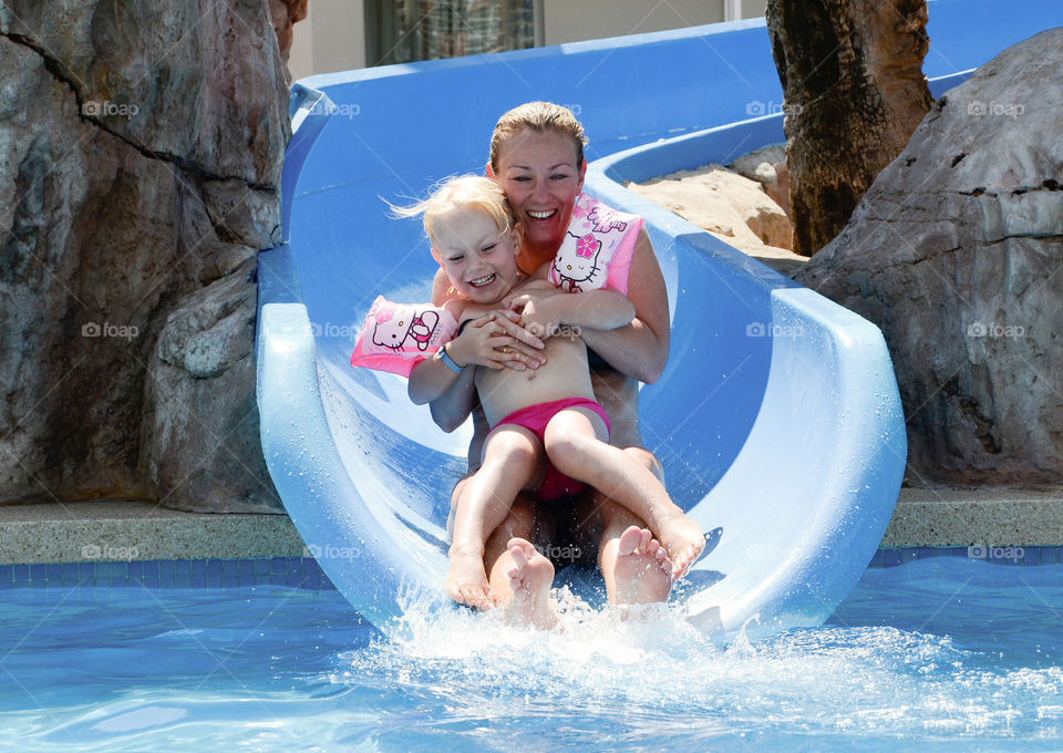 Mother and daughter sliding at water park