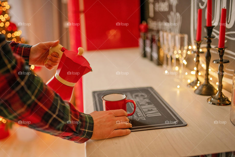 Festive winter cozy kitchen interior with garlands, decorations and gifts.  Christmas dinner at the decorated table.