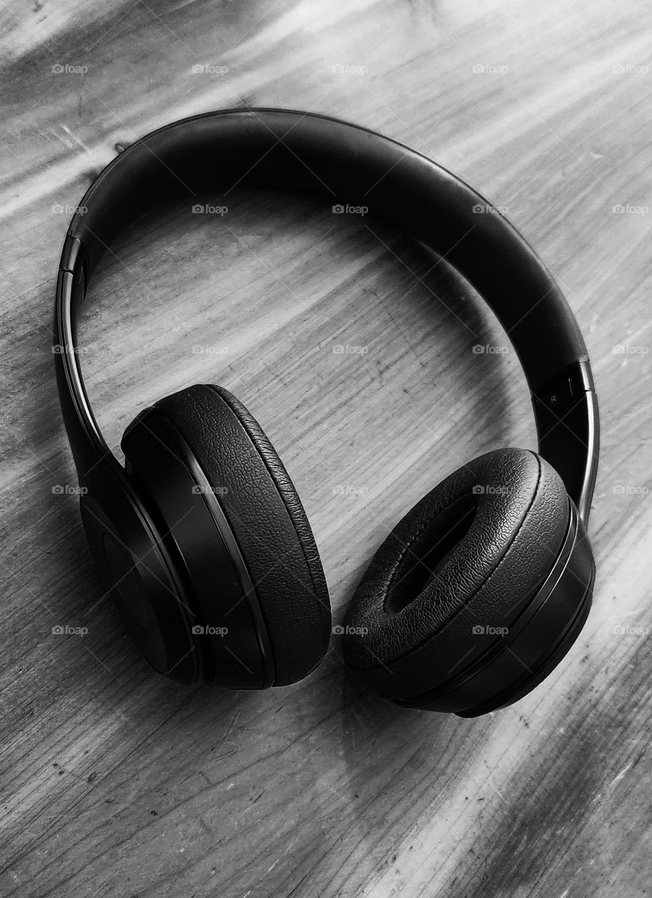 black and white close-up view of black headphones on a wood surface