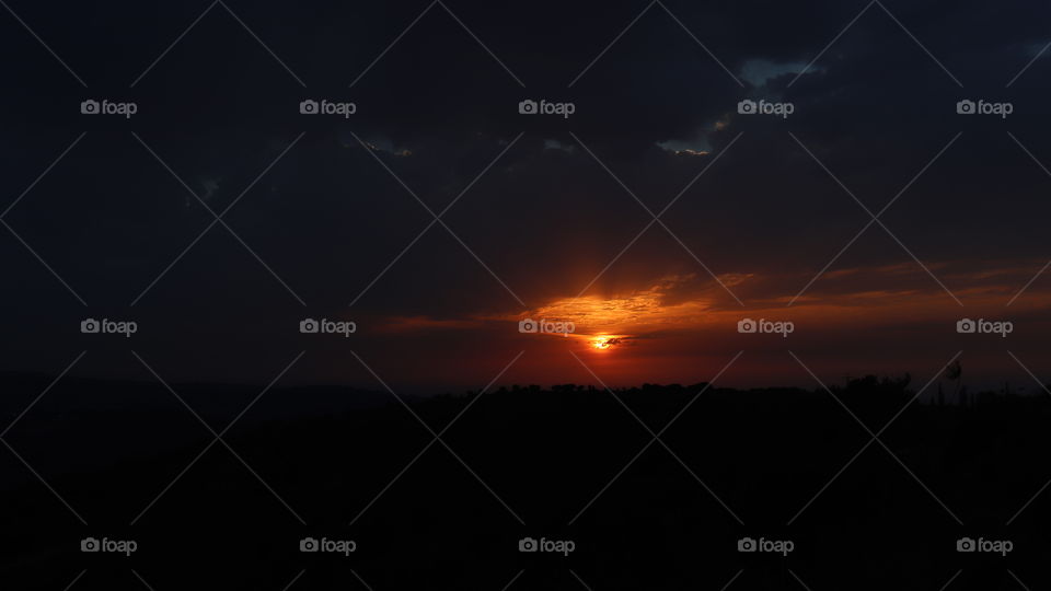 An orange sunset with black clouds and sky