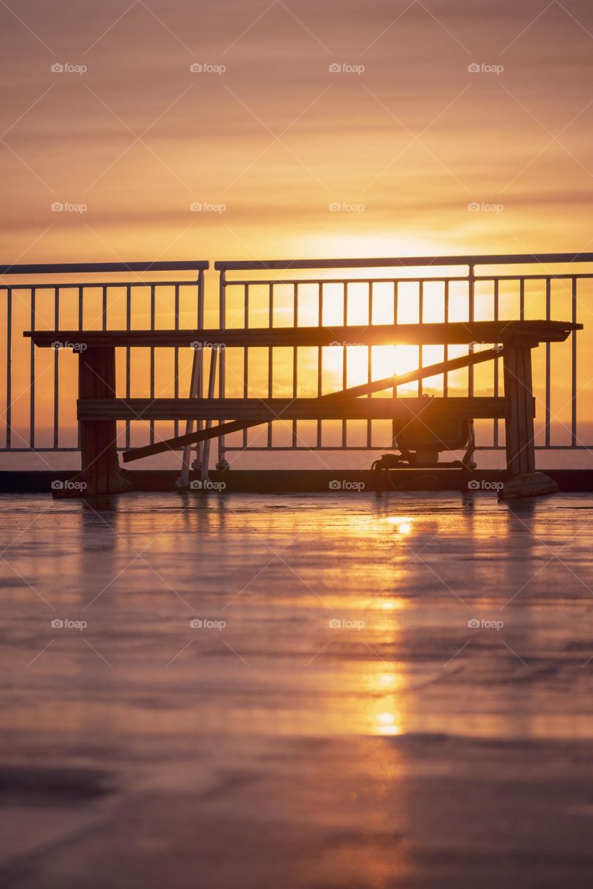 a bench stands near the ferry's railing against the backdrop of dawn in the Baltic Sea