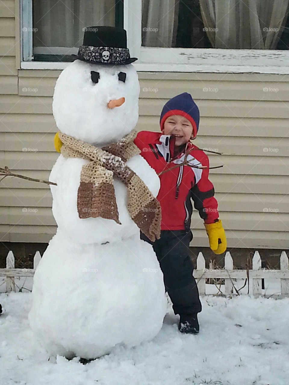 Smiling boy standing besides snowman