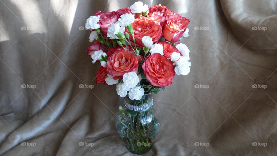 Bouquet of red roses and white carnations in a diamond laced base