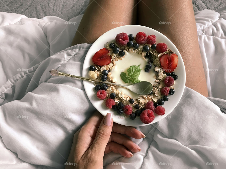 Young woman enjoying her healthy breakfast at cozy bed 