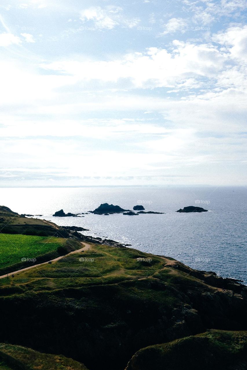 View Of Green Hills By Dark Blue Water