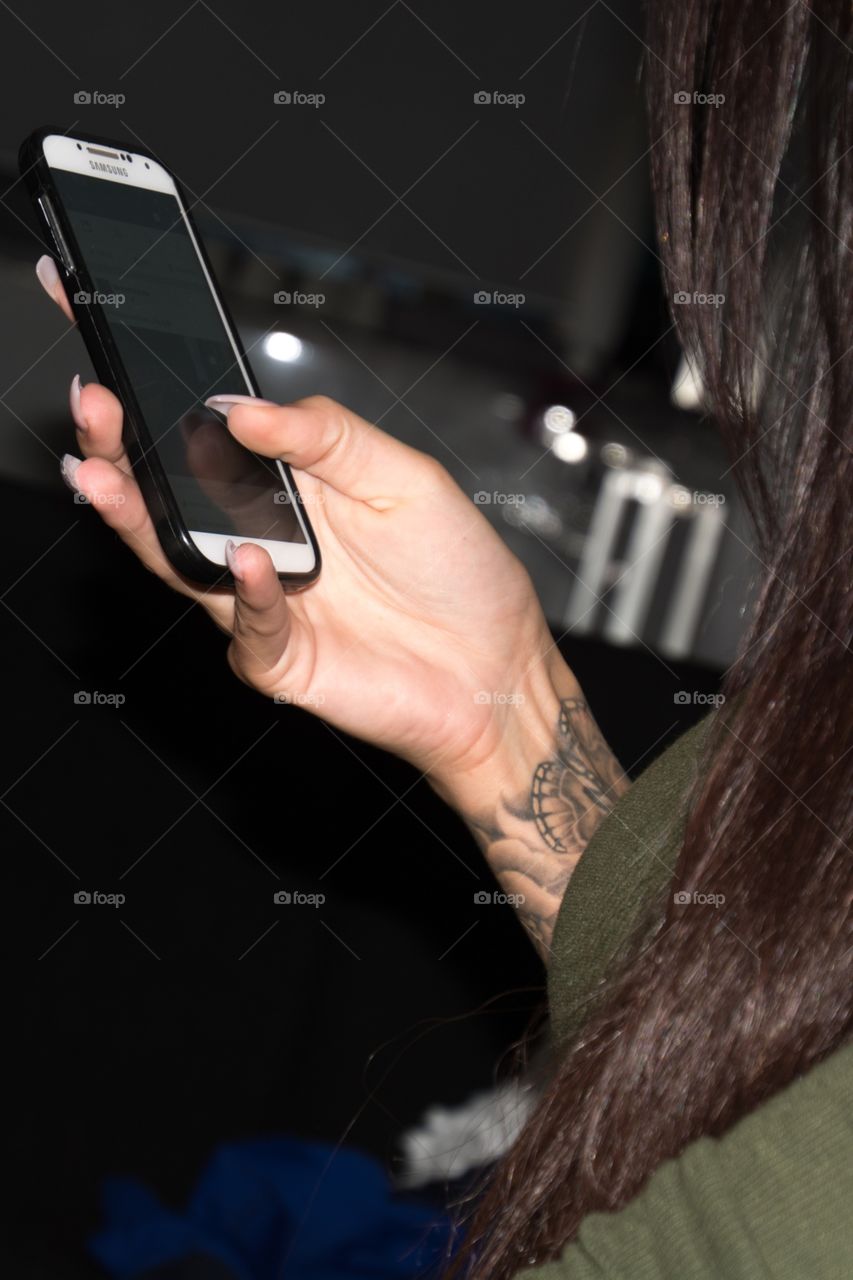 A woman's hand busy with her mobile phone