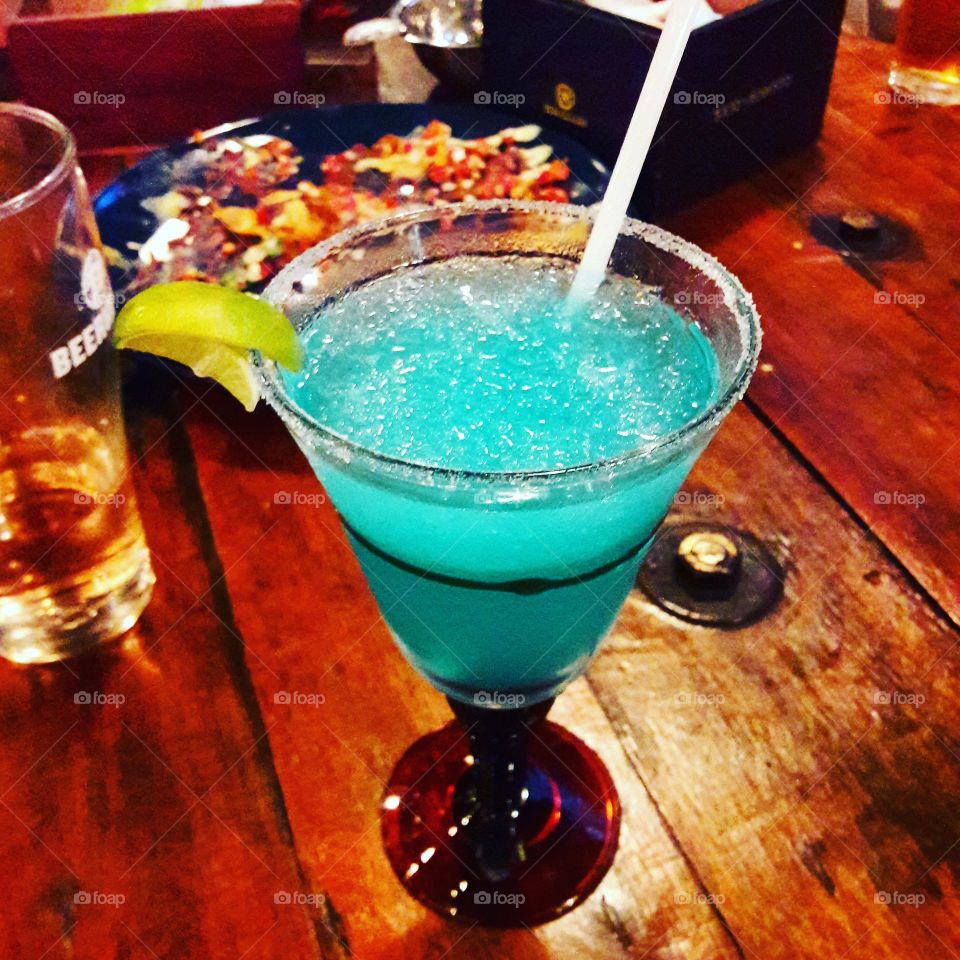 A Blue Margarita is a cocktail consisting of tequila, triple sec, and lime juice often served with salt on the rim of the glass. The drink is served shaken with ice, blended with ice, or without ice.