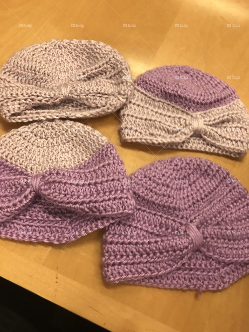 Four purple crocheted baby hats