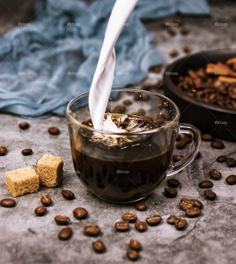 milk is poured into a cup of coffee