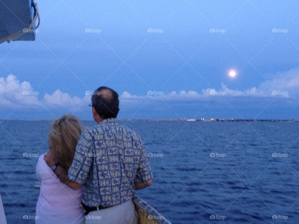 Parents watching the moon rise over the harbor