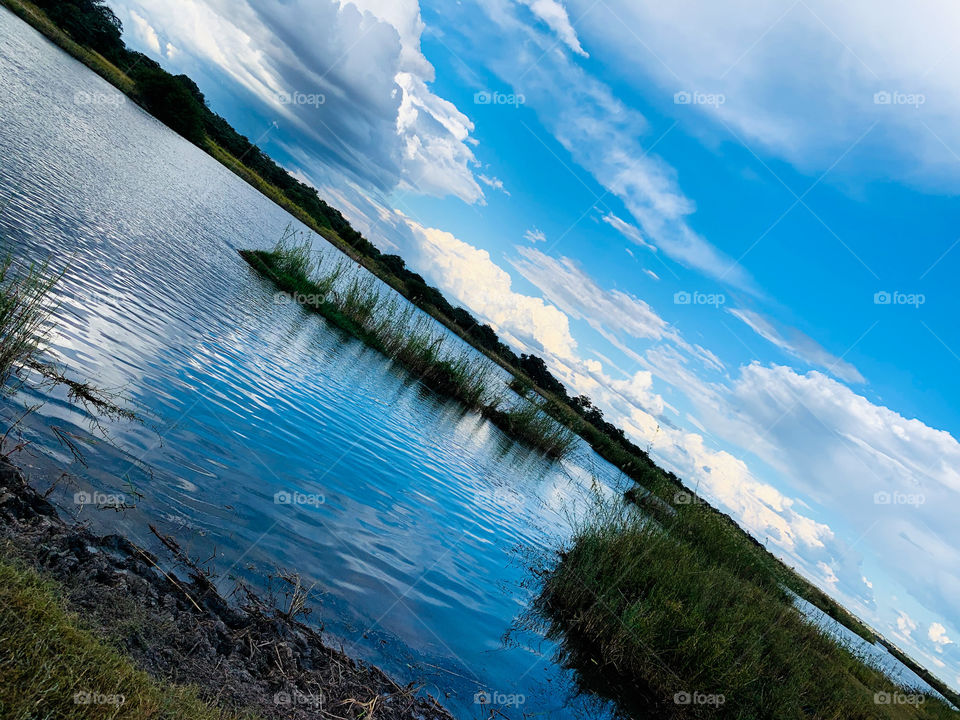 A diagonally divided picture of a natural view of a cloudy sky over the River water. 