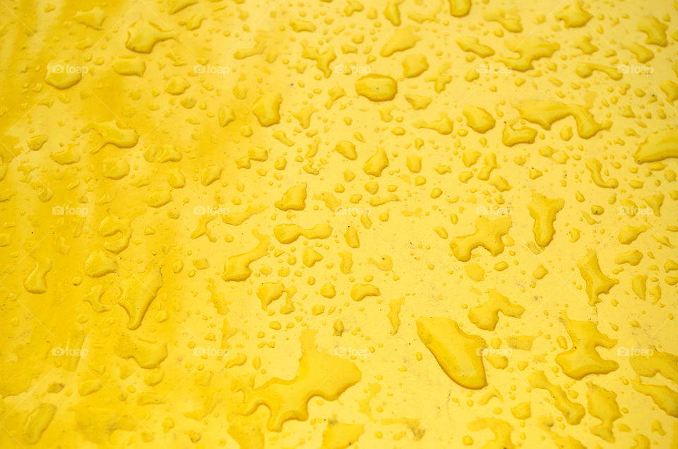 Full frame shot of water drops on yellow car in Berlin, Germany.