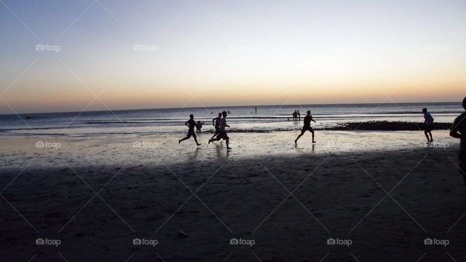 Boys playing soccer in the beach 