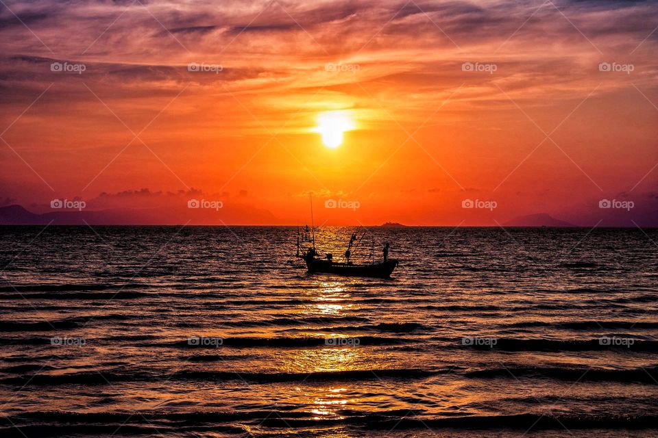 A lone fishing boat at sunset in the ocean, near Kep, Cambodia