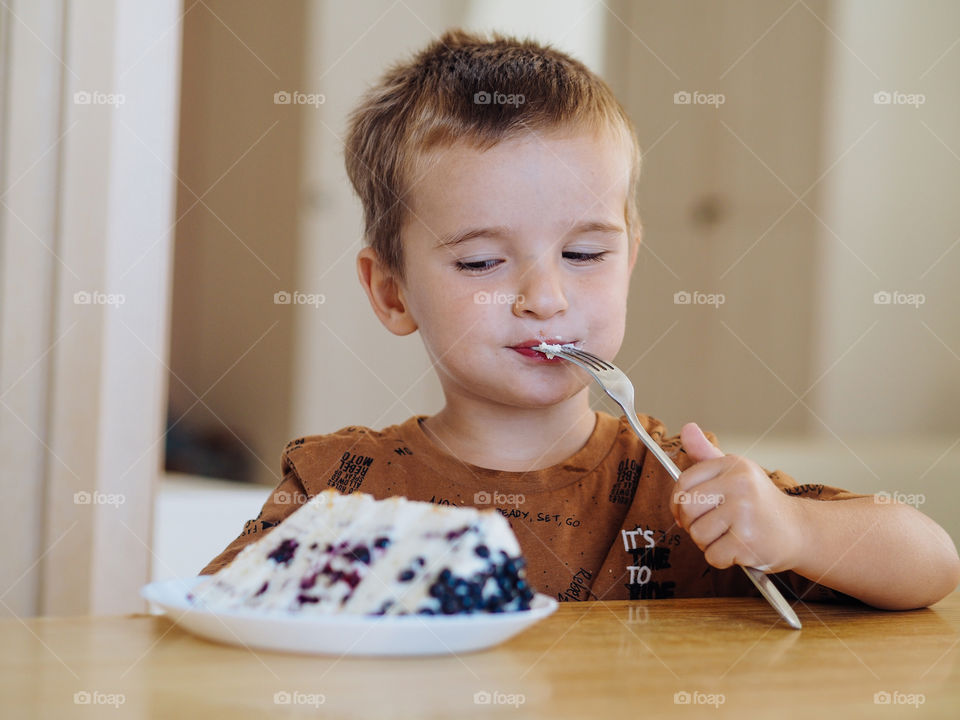 Pretty Caucasian toddler boy eating a cake 
