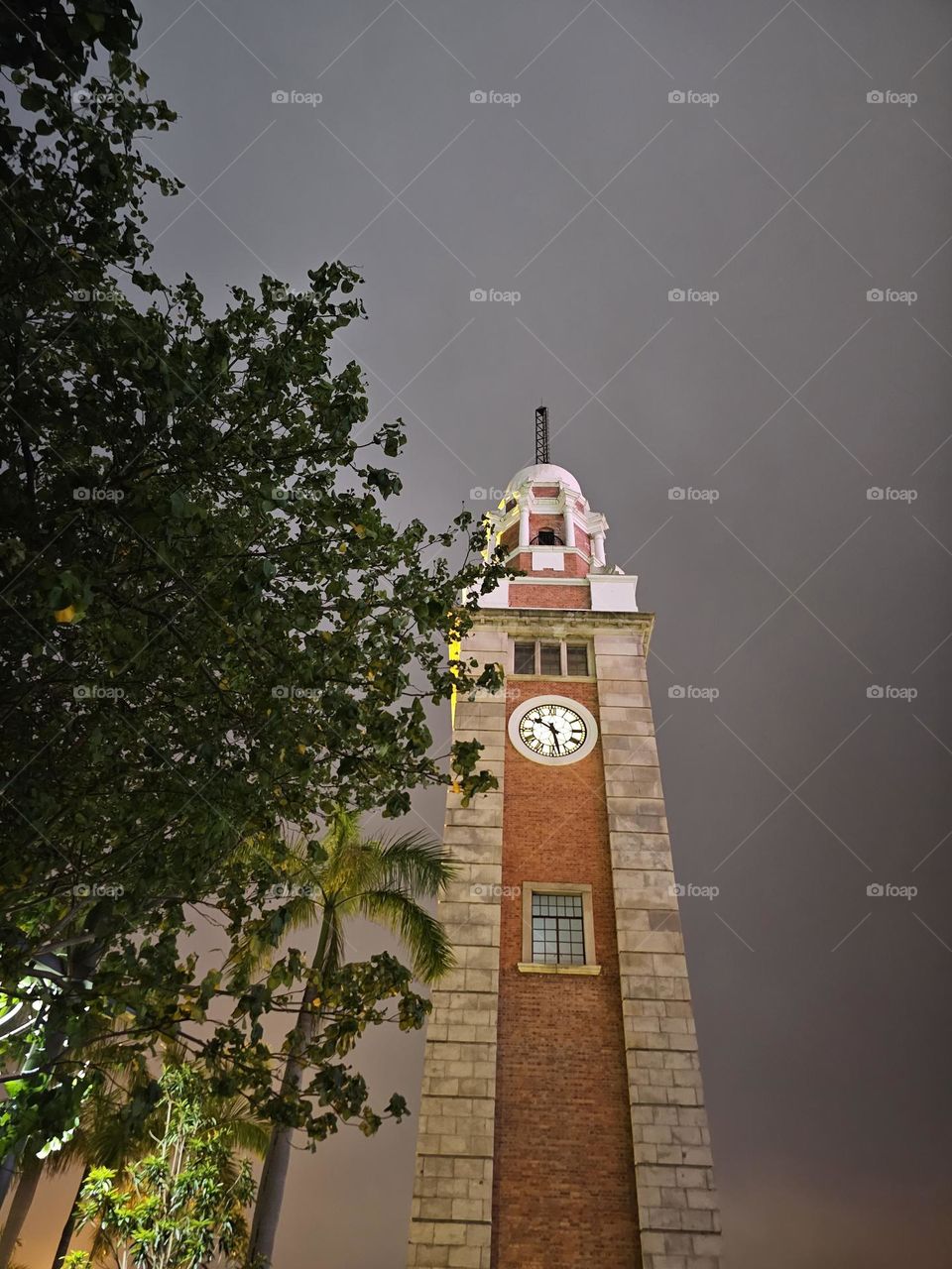 drizzling night at TST Star Ferry Pier looking up at the clock tower