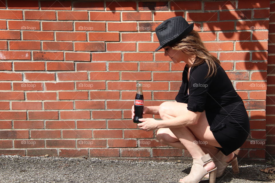 Female in front of brick wall holding Coca Cola 