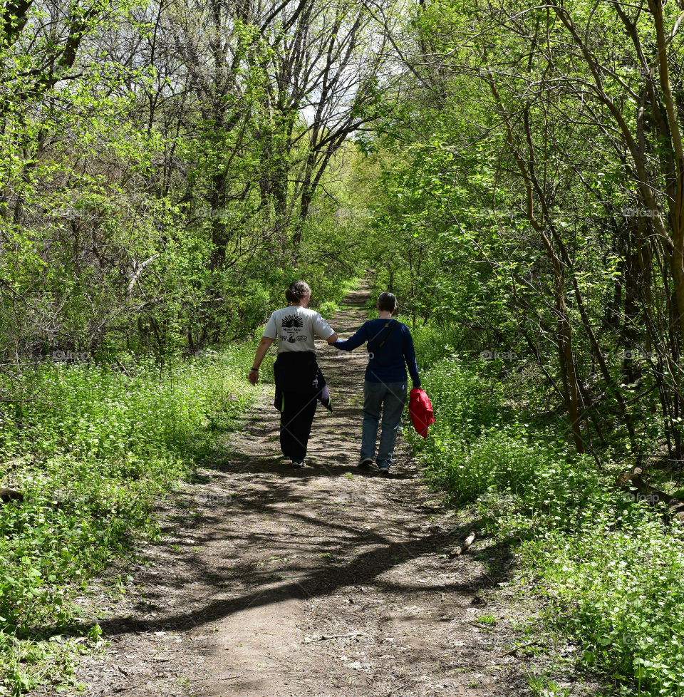 Female couple holding hands on a wooded path