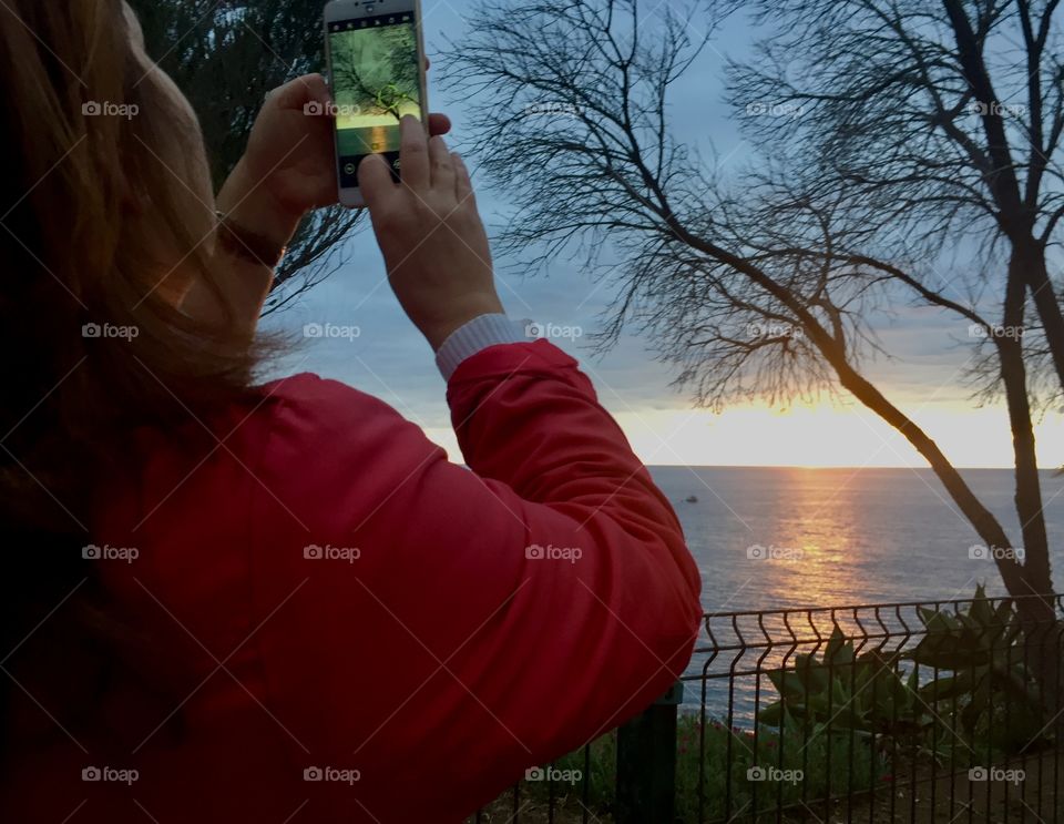 A woman taking pictures of the sunset