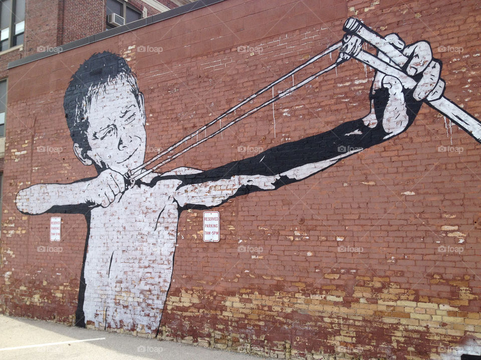 A boy takes aim with his slingshot in this urban mural.