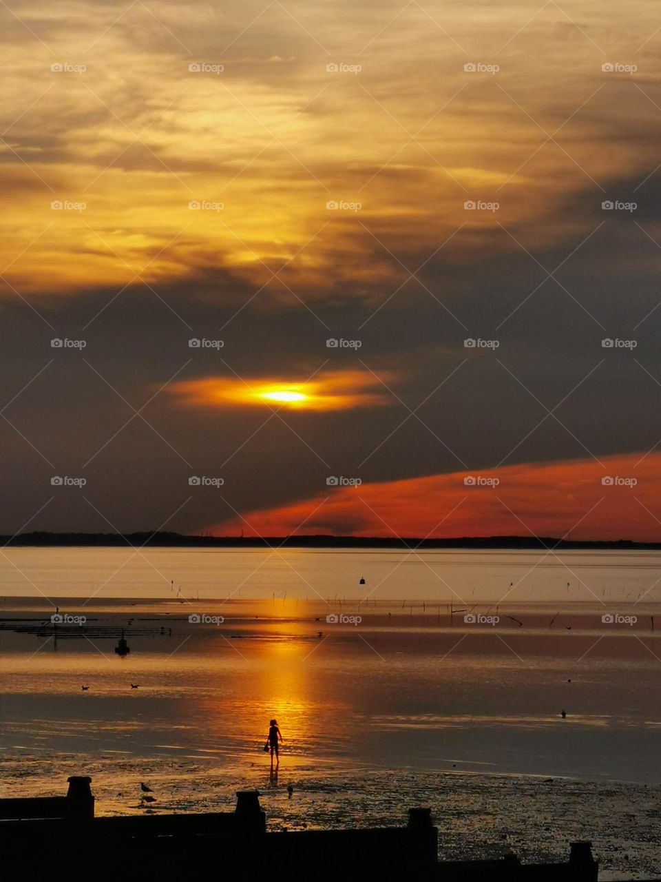 Beautiful sea sunset and a girl in the rays of the setting sun.