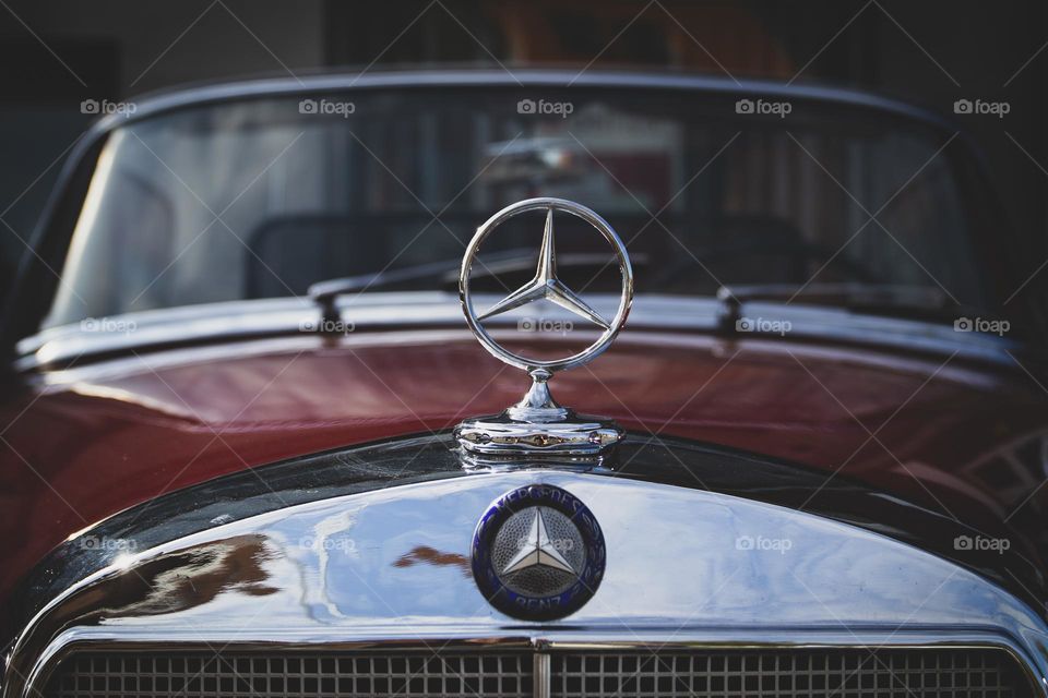 A close up portrait of the Mercedes benz logo on the hood of a vintage oldtimer car