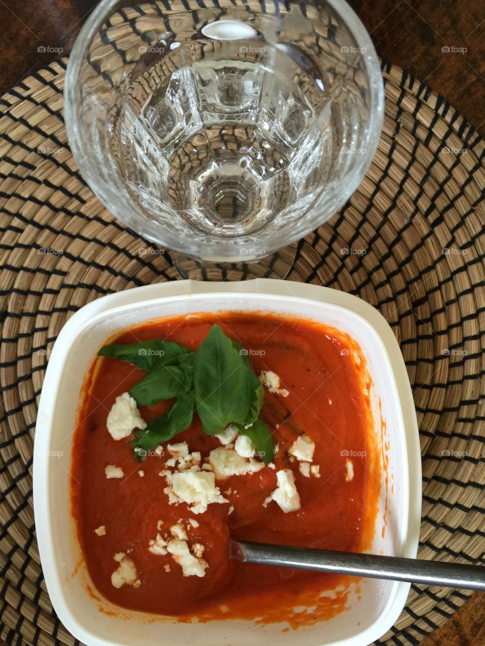 Tomato soup with feta and basil and a glass of water. Tabletop shot