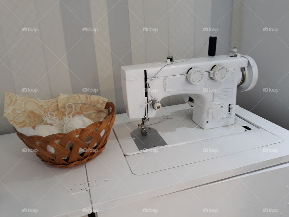 швейная машинка белого цвета и корзина с вязанием