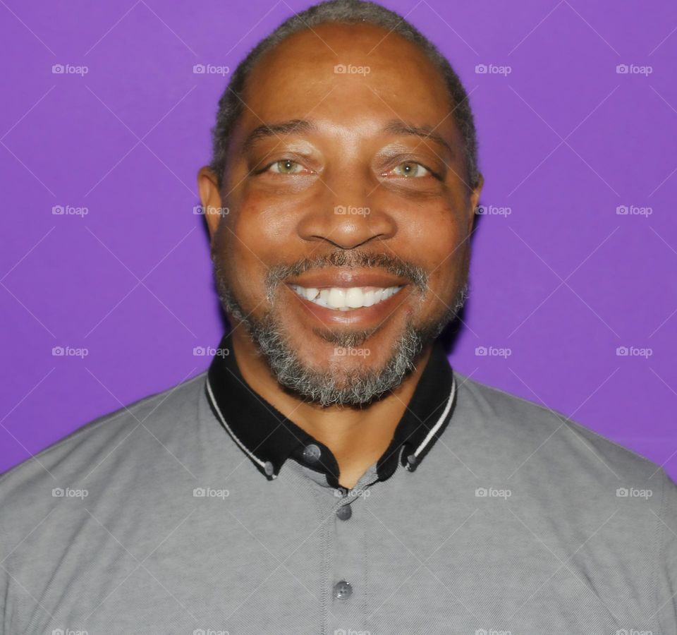 male model looking at the camera with a smile and a purple background