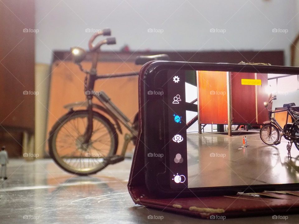 Take object about old toy bicycle with mobile phone