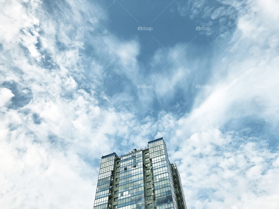 Top of modern building in front of blue cloudy sky
