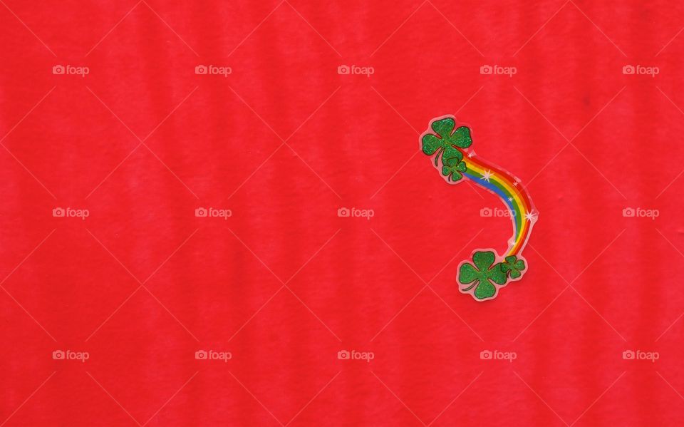 An Irish Rainbow sticker with green shamrocks on a red background.