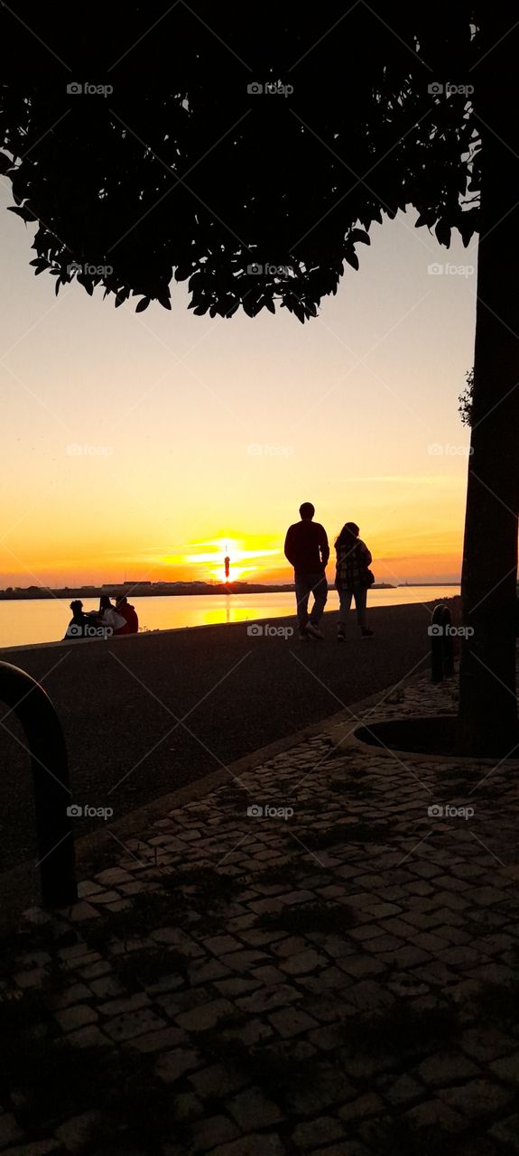 couple walking by the river watching sunset