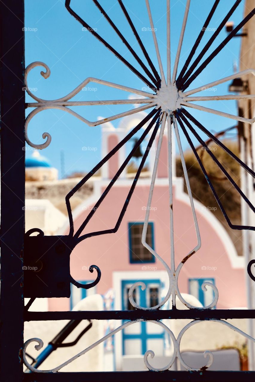 Standing behind ornamental metal door looking at architecture in a village 