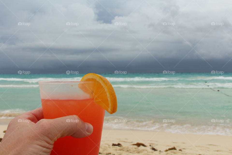 hanging tekila sunrise glass on the caribbean beach of playa del carmen