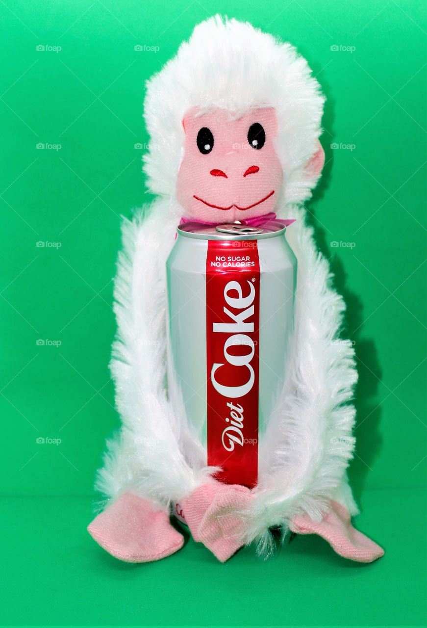 a white stuffed animal holding a can of Coca-Cola with a green background