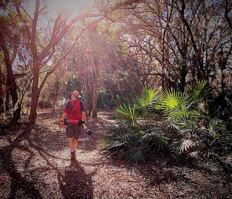 A photographer trekking into the sparkling sunlight for exercise of the body and soul.