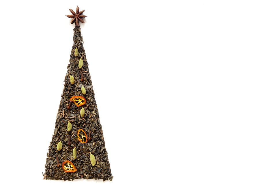 Christmas tree made of green tea, dried cumquat, cardamom, star anise on white background