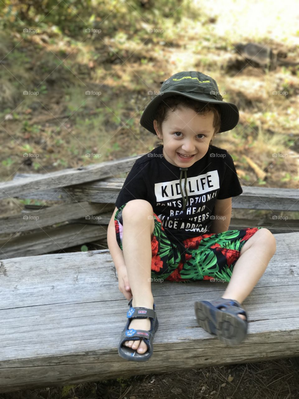 An adorable little boy wearing a hat out hiking in the woods of Central Oregon on a sunny summer day. 