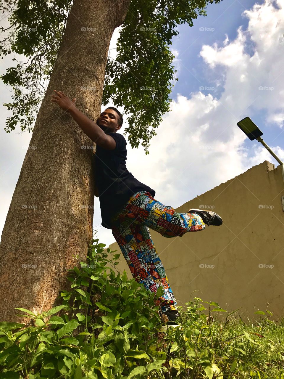 Man hugging tree against blue sky 