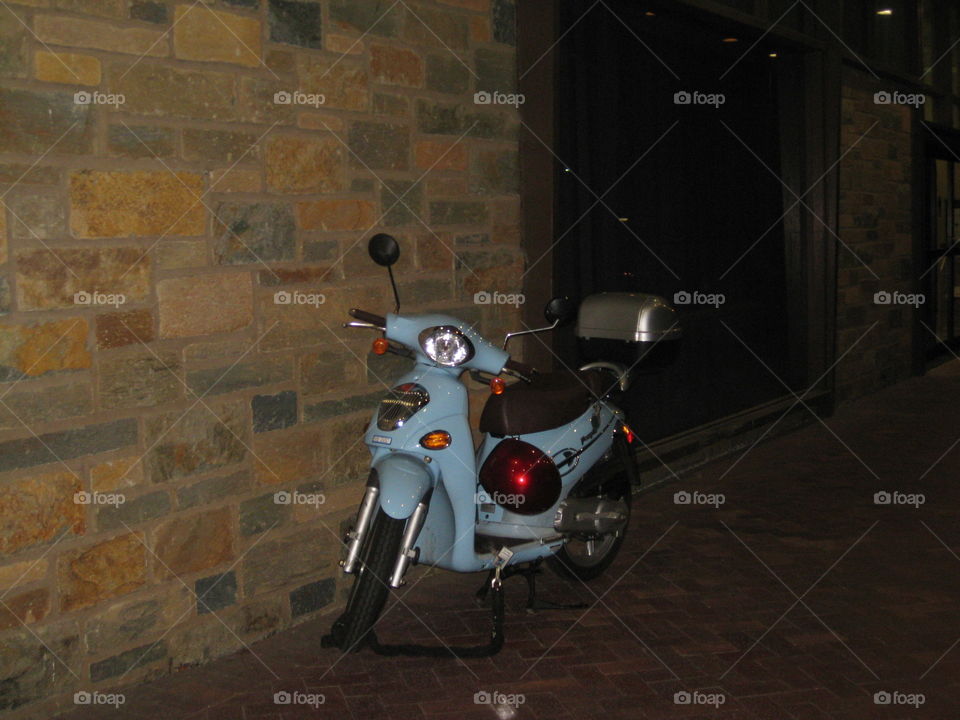 Bright blue scooter leaning against the wall of a building