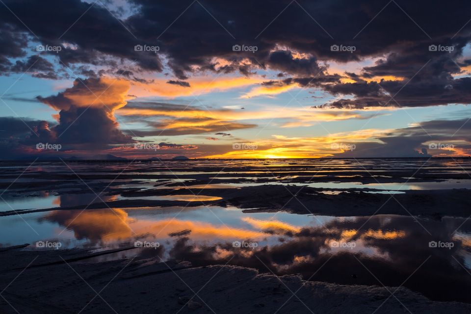 Sunset in Yuni salt flat. Dramatic sunset in Yuni salt flat in Bolivia. Reflection of colorful sky from water