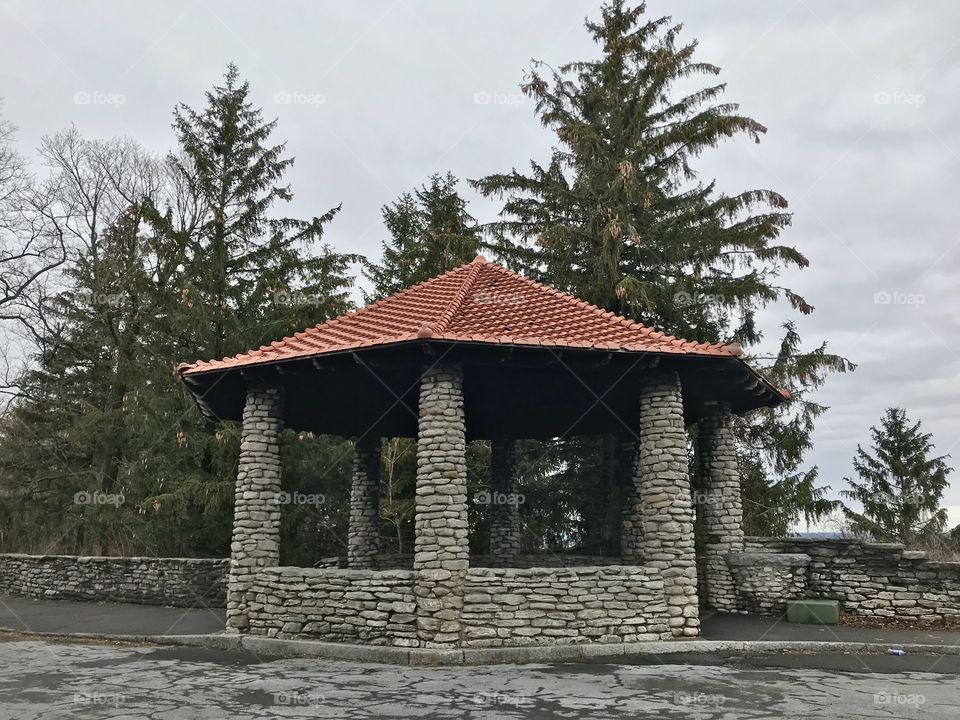 Stone gazebo in front of pine trees