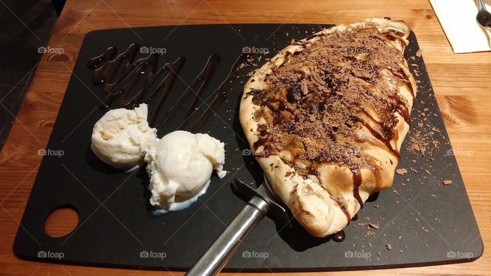 Banana Nutella calzone covered with gooey, delicious chocolate syrup and cool vanilla ice cream