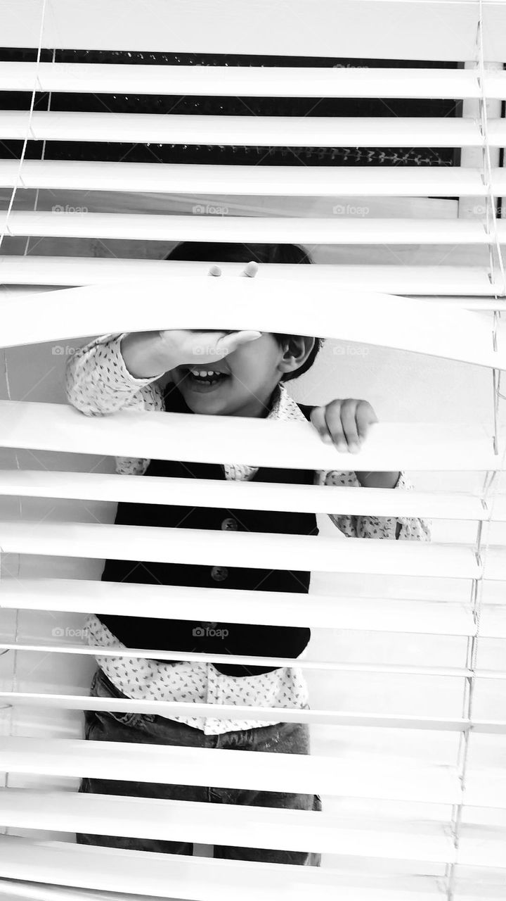 Little Boy Hiding Behind The Blinds