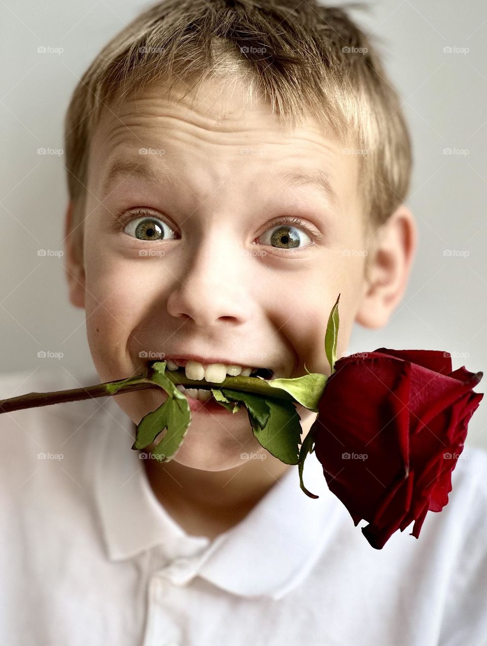 smiling boy with a rose in his mouth