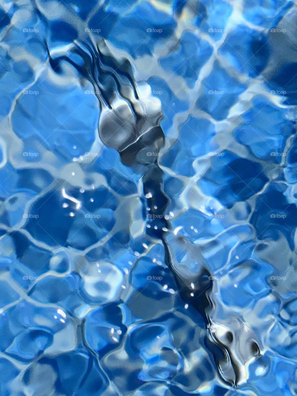 Silver plated fork in blue tiled agitated swimming pool