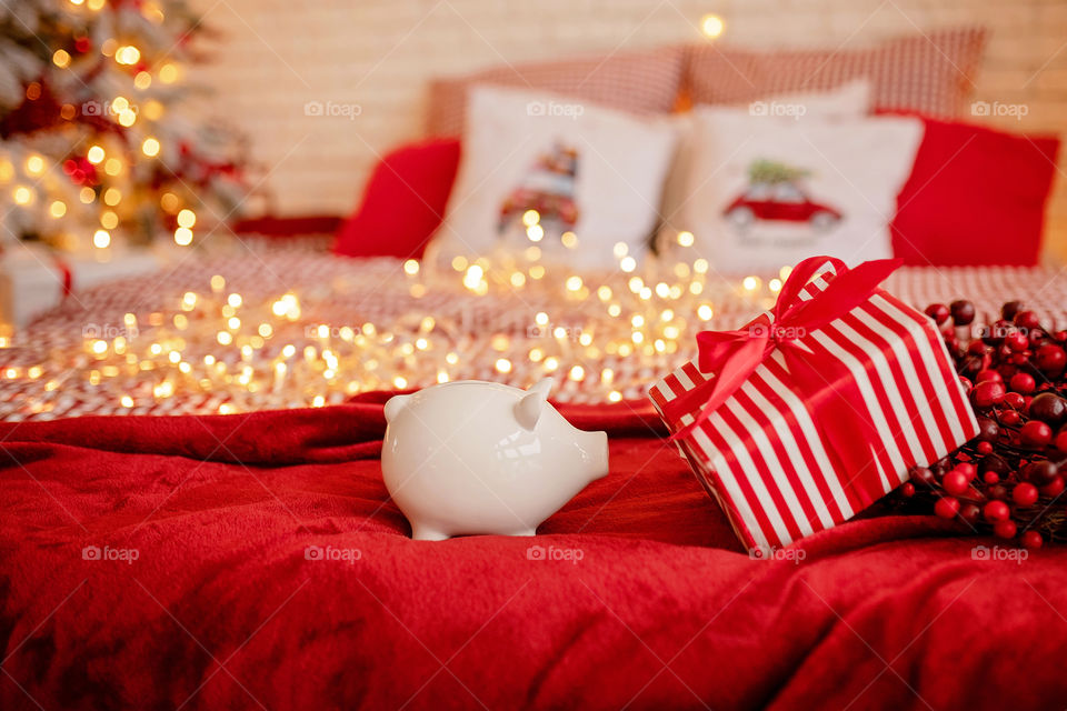 piggy bank with 100 dollars banknote in festive New Year atmosphere of scenery.  Magical bokeh with Christmas tree and bright lights.