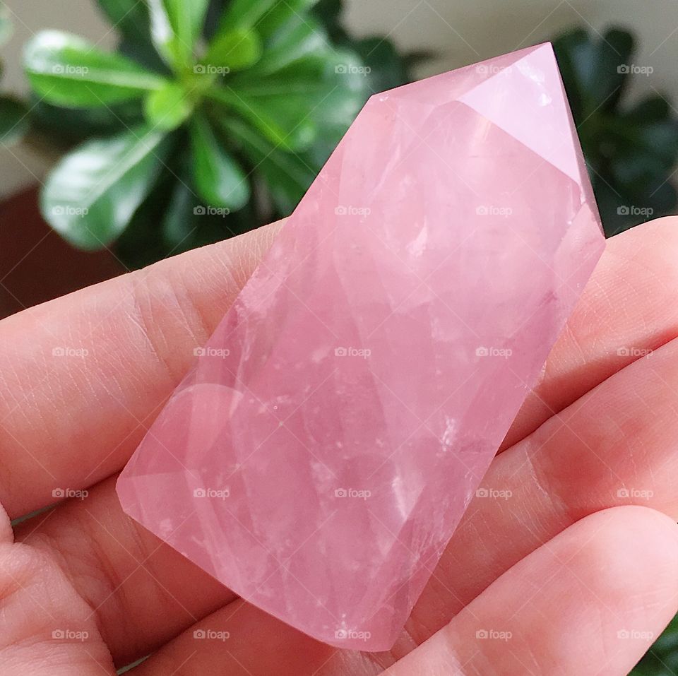 A polished pink rose quartz crystal tower point.