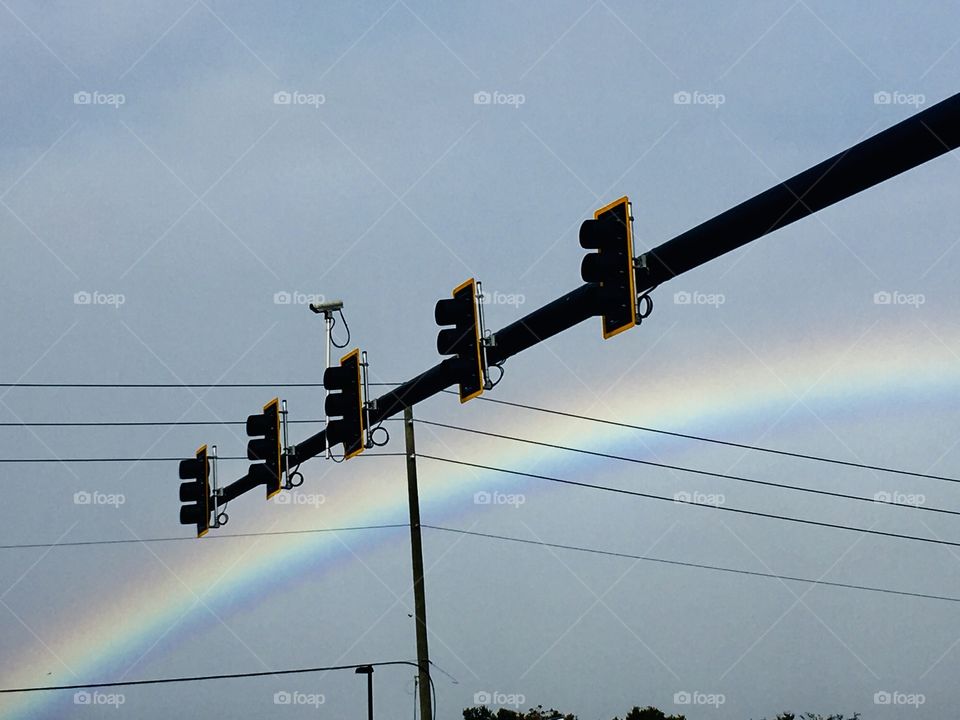 Rainbow over power lines and traffic lights 